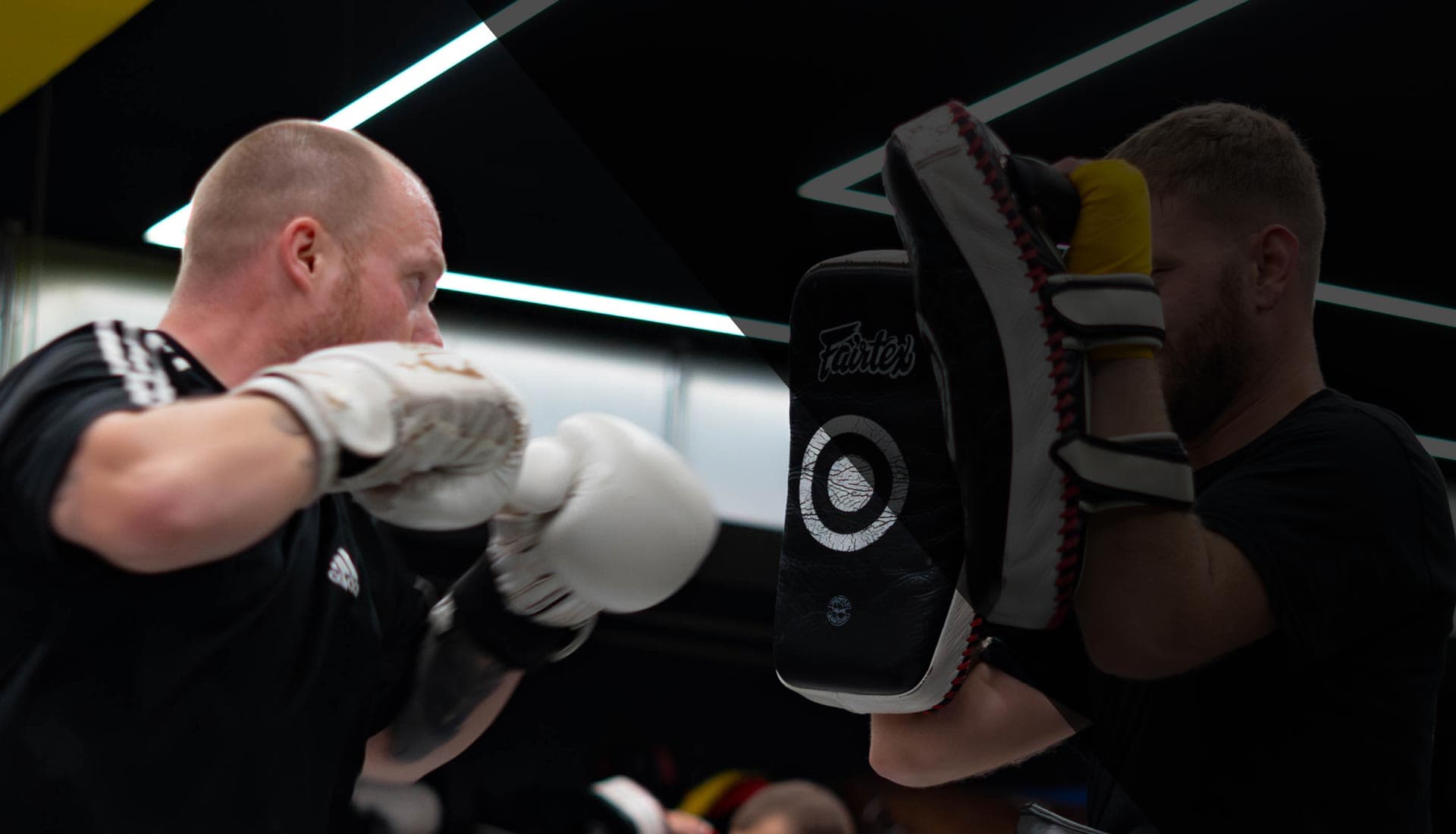 Man punching pads, dark interior with lime ceiling strip